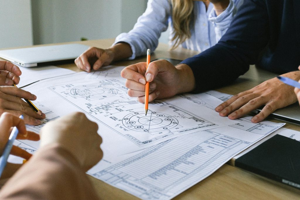 Team working on engineering plans, discussing ideas at an office meeting.