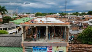 Aerial shot of a building under construction in an urban area with cloudy sky.